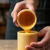 Person pouring wax into a candle container